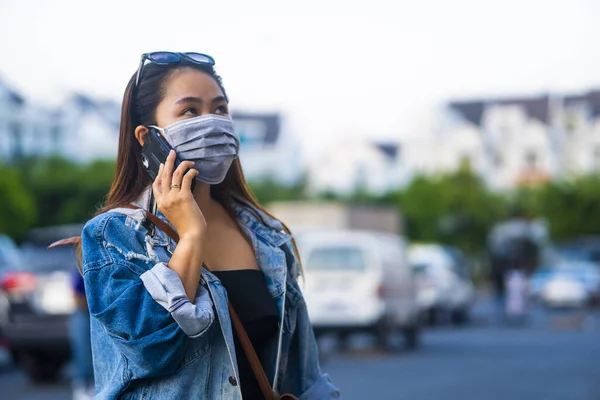 Sokakta Cep Telefonu Kullanırken Ameliyat Maskesi Takan Genç Bir Kadın — Stok fotoğraf