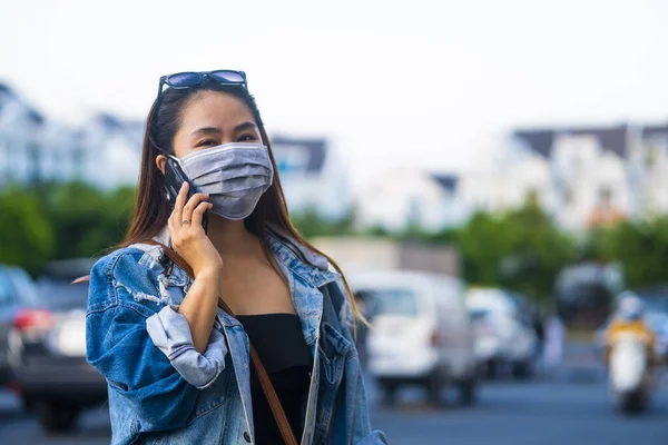 Sokakta Cep Telefonu Kullanırken Ameliyat Maskesi Takan Genç Bir Kadın — Stok fotoğraf