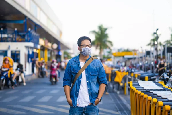 Portrait of young man wearing a protective mask, outside the supermarket  to prevent germs, toxic fumes, and dust. Prevention of bacterial infection Corona virus or Covid 19 in the air around the streets and gardens.