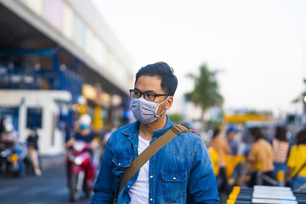 Portrait of young man wearing a protective mask, outside the supermarket  to prevent germs, toxic fumes, and dust. Prevention of bacterial infection Corona virus or Covid 19 in the air around the streets and gardens.