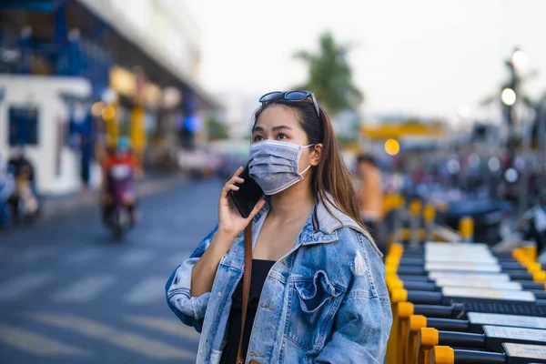 Sokakta Cep Telefonu Kullanırken Ameliyat Maskesi Takan Genç Bir Kadın — Stok fotoğraf