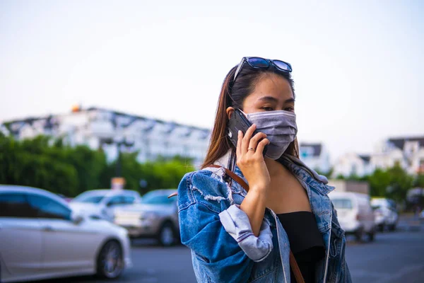 Sokakta Cep Telefonu Kullanırken Ameliyat Maskesi Takan Genç Bir Kadın — Stok fotoğraf