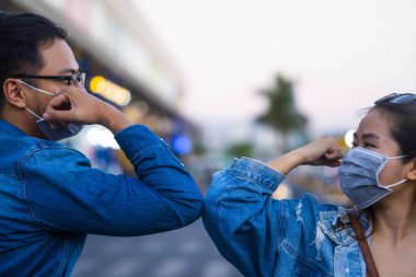 Coronavirus 'un (COVID-19) yayılmasını önlemek için yeni bir selamlama yöntemi. İki kişi (bir erkek ve bir kadın) sarılmak ya da tokalaşmak yerine dirseklerini birbirine vurur.