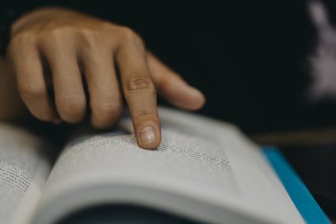 Genç adam ameliyat maskesi takıyor ve Vietnam 'da bir kafede kitap okuyor.