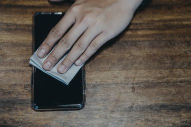 Covid-19 hastalığını önlemek için cep telefonlarını temizliyorum. Güvenlik için akıllı telefonun mendillerine alkol, dezenfektan, Covid-19 virüsü enfeksiyonu, kirlilik, mikroplar, sık sık dokunulan bakteriler..