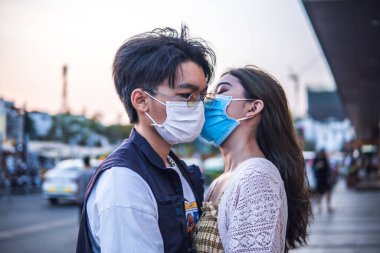 Yeni nesil koruyucu maskeler takan ve birbirlerini öpen genç çiftler, virüs önleme ve insanların konseptini yaydı.