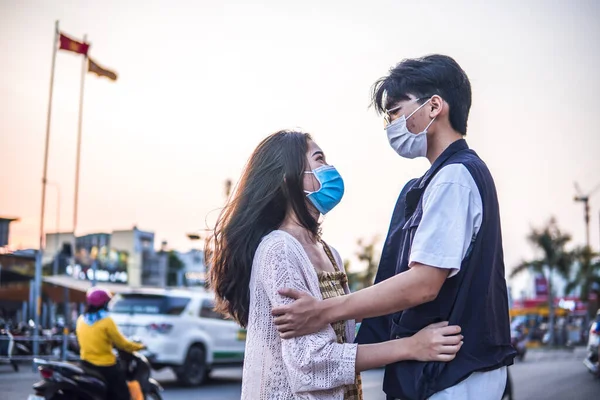 若い千年紀のカップル抱擁と保護面マスクを身に着けている ウイルス拡散防止と人々は株式を概念 — ストック写真