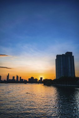 River City manzarası alacakaranlık günbatımında. Nehirde sakin suyu olan bir tekne. Bitexco kulesi olan Hochiminh şehri Saigon Vietnam şehir merkezi. Saigon nehri manzarası bulutlu ve güneşli