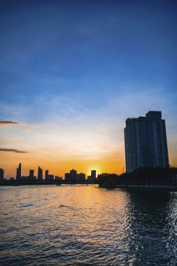 River City manzarası alacakaranlık günbatımında. Nehirde sakin suyu olan bir tekne. Bitexco kulesi olan Hochiminh şehri Saigon Vietnam şehir merkezi. Saigon nehri manzarası bulutlu ve güneşli