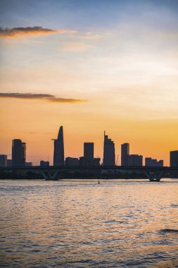 River City manzarası alacakaranlık günbatımında. Nehirde sakin suyu olan bir tekne. Bitexco kulesi olan Hochiminh şehri Saigon Vietnam şehir merkezi. Saigon nehri manzarası bulutlu ve güneşli