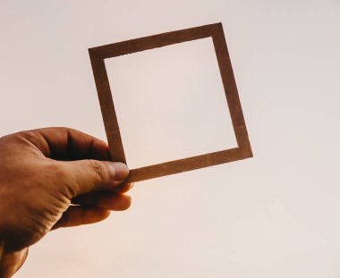 El ele tutuşan boş bir çerçeve ve doğal bir bokeh arka plan. Metin kavramı.