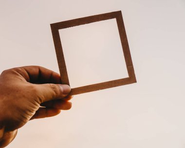 El ele tutuşan boş bir çerçeve ve doğal bir bokeh arka plan. Metin kavramı.