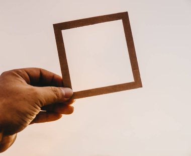 El ele tutuşan boş bir çerçeve ve doğal bir bokeh arka plan. Metin kavramı.