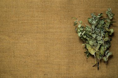 Eski çuval bezi üzerinde kurumuş sarı ve kırmızı gül yapraklarının üst görüntüsü. Romantik ve hüzünlü kavramsal geçmiş.