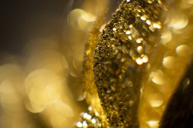 Bokeh 'in soyut altın arka planı. Arka planda tatil ışıkları. Bokeh odaklı ışıklar ve yıldızlarla şenlikli soyut arkaplan