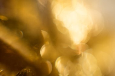 Bokeh 'in soyut altın arka planı. Arka planda tatil ışıkları. Bokeh odaklı ışıklar ve yıldızlarla şenlikli soyut arkaplan