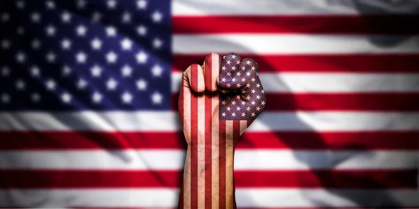 Banner of Flag of Unites States of America painted on male fist, fist flag, country of USA, strength, power, concept of conflict. On a blurred background with a good place for your text.