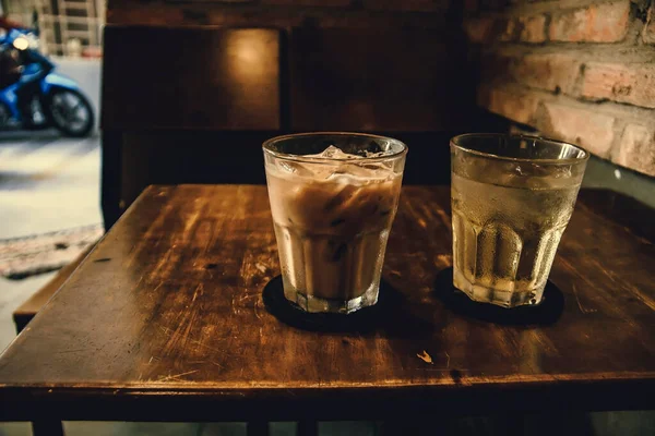 Vietnamese Milk Coffee on Wooden Table. Traditional Hot Drinks in Vietnam. Close-up Vietnamese Drip Coffee and Ice mug served with milk, Iced black coffee.