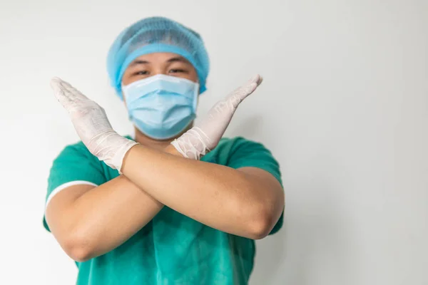 A doctor wearing uniform including mask, goggle to protect virus and show stop hand gesture for social distancing. and show stop hands gesture for stop corona virus outbreak. Covid-19, medical concept