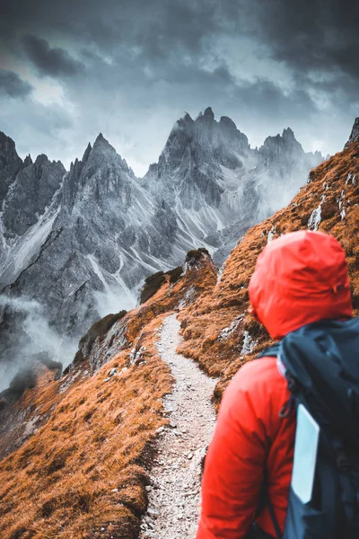 Back view of a hiker trekking on the mountains and contemplating dramatic panorama.