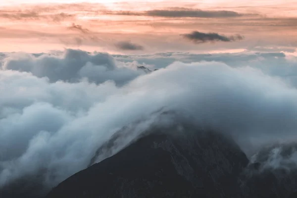 背景照片为高山山谷中的低云 生机勃勃的蓝橙色天空 日出或日落的景色 可以看到群山和山峰在云中的最高峰 斯洛文尼亚阿尔卑斯山脉冬季高山景观 — 图库照片