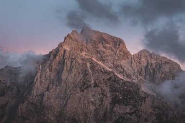 Bir dağ vadisinde alçak bulutların arkaplan fotoğrafı, canlı mavi ve turuncu pembe gökyüzü. Gün doğumu veya gün batımı bulutların arasından yükselen dağ ve tepelerin manzarası. Slovenya Alplerinin manzarası gibi kış alpleri