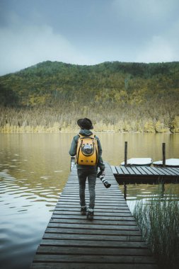 Yürüyüş, turizm ve doğa konsepti - Sırt çantalı genç gezgin ve kedisiyle Romanya 'nın Transilvanya kenti Sfanta Ana Gölü iskelesinde duruyor