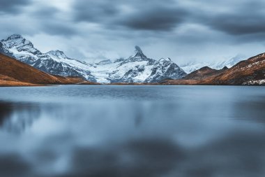 Moody picturesque view on Bachalpsee lake in Swiss Alps mountains. Snowy peaks of Wetterhorn, Mittelhorn and Rosenhorn on background. Grindelwald valley, Switzerland. Landscape photography clipart
