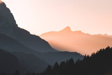 Dağların siluetleriyle turuncu ve sarı günbatımı. Gradyan canlı doğa arkaplanı
