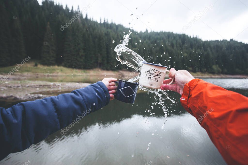 Close up human hands splashing mugs with water by the lake