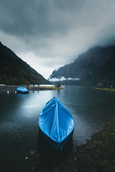 在克隆塔尔湖 一艘船停泊在近岸处的令人心酸的风景 位于瑞士格劳鲁斯克隆塔尔的美丽而阴郁的风景 背景是多雾的群山 — 图库照片