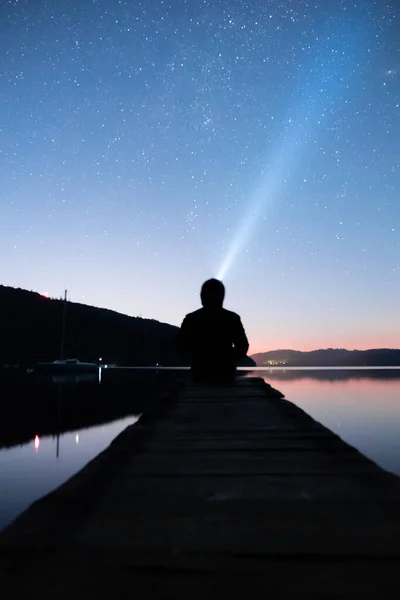 Человек смотрит на ночное небо с фонариком — стоковое фото
