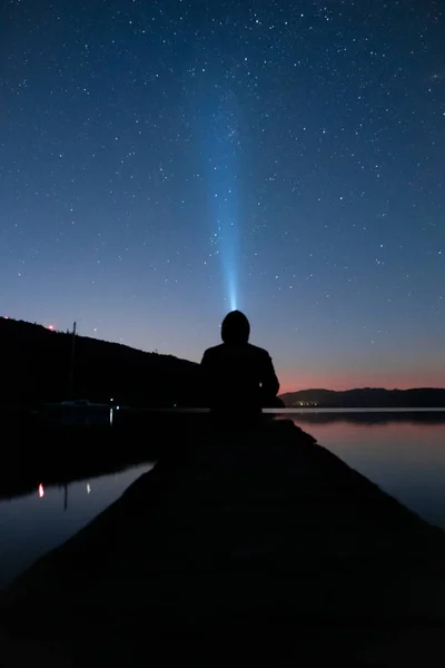 Man gazing over the night sky with the flashlight