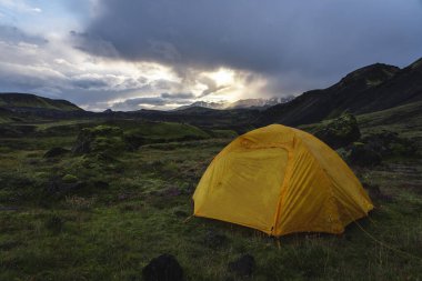 Yellow camping tent in an open moss field during sunset. Shot on adventure in Icelandic highlands