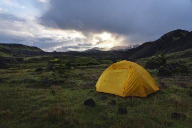 Yellow camping tent in an open moss field during sunset. Shot on adventure in Icelandic highlands