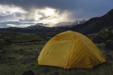 Yellow camping tent in an open moss field during sunset. Shot on adventure in Icelandic highlands