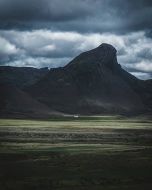 Önünde küçük beyaz evi olan egemen dağ ışıkla aydınlatılıyor.
