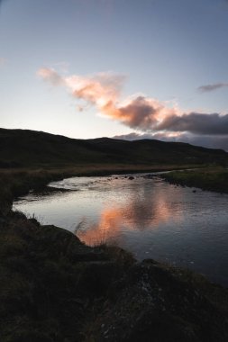 Güneşin doğuşu sıcak pınarın yanında Suyun yansımasıyla