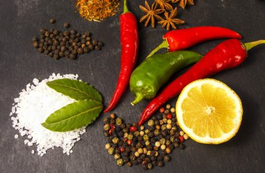 Fuar yakın taze organik biber, yarım limon, mont bırak, tuz ve ANIS koyu arka plan üzerinde. Sağlıklı horoz, taş kesme tahtaları, chili biber, kırmızı ve yeşil biber. 