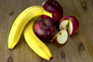 Fuar yakın taze organik muz, yarım ve tam kadar elma, gri ahşap zemin, üzerine taze nane sağlıklı horoz.