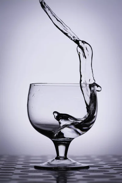 Water splash in glass, columbia blue background. — Stock Photo, Image