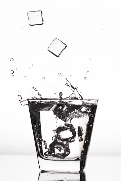 Glaçons éclaboussant dans le verre, glaçons tombés dans le verre d'eau, eau douce, eau froide, isolé sur fond blanc, bleu, argent, bleu . — Photo