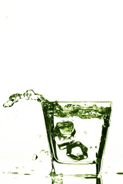 Παγάκια εκτινάξεις σε πράσινο γυαλί, παγάκι πέσει μέσα σε ποτήρι νερό, φρέσκο, κρύο νερό, απομονώνονται σε λευκό, πράσινο φόντο. — Φωτογραφία Αρχείου