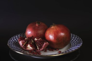 Fuar Granat vintage Rus porselen tabak siyah arka plan, tam ve yarım garnet, taze doğal meyve. yakın çekim.