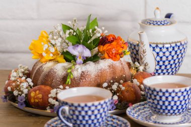 Vintage Rus fincan çay ve ahşap masa nad beyaz tuğla zemin üzerine su ısıtıcısı ile Doğu Fuar Doğu kek, renkli Doğu yumurta ve menekşe kardelen. Mutlu Doğu.