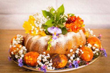 Doğu Fuar Doğu kek, renkli Doğu yumurta ve ahşap masa nad beyaz tuğla zemin üzerine frezia çiçekli mor kardelen. Mutlu Doğu, vintage Rus plaka.