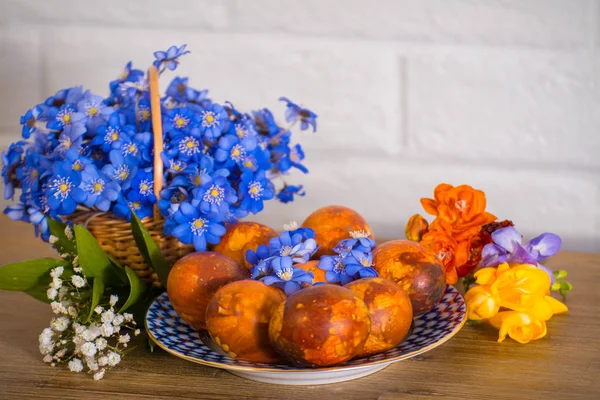Doğu Fuar Doğu kek, renkli Doğu yumurta ve ahşap masa nad beyaz tuğla zemin üzerine frezia çiçekli mor kardelen. Mutlu Doğu.
