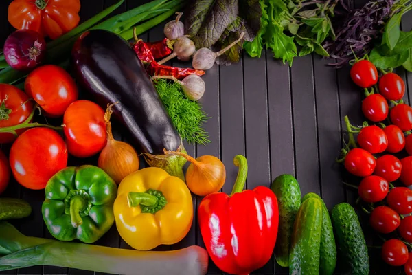 新鮮な有機野菜、生有機野菜、赤唐辛子、トマト、キュウリ、玉ねぎ、ニンニク、黒の木製テーブルの上に組成の博覧会をクローズ アップ. ロイヤリティフリーのストック画像