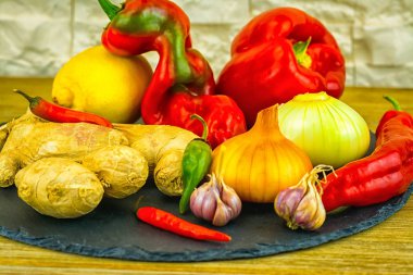 Fuar yakın çekim taze organik sebze, kompozisyon ile çeşitli ham organik sebzeler, kırmızı biber, soğan ve sarımsak, yeşil biber ve kırmızı biber biber sıcak ve siyah tuğla masaya zencefil.