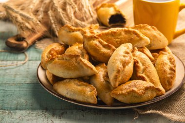 Yeşil ahşap masada haşhaş tohumlu taze çörek sergisi. Ev yapımı çörek..